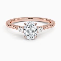 a rose gold engagement ring with an oval cut diamond in the center and three stones on each side