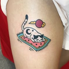 a person with a tattoo on their thigh that has an image of a cat sleeping on a blanket