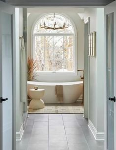 a bathroom with a tub, toilet and window