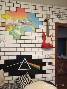 a guitar hanging on the wall next to a bed in a room with white brick walls