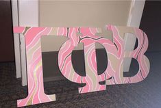 the letters are made out of wood and painted pink, brown and white designs on them