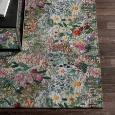 an area rug with flowers on it and a book laying on the floor next to it