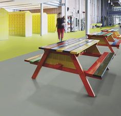 several benches are lined up in the middle of an empty building with people walking by