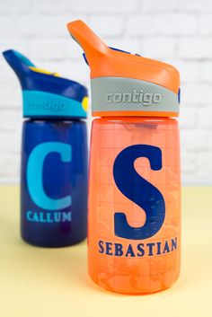 two orange and blue water bottles sitting next to each other on top of a table