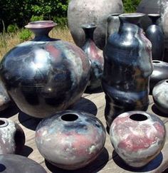 several different sized vases sitting on a table outside with grass in the back ground