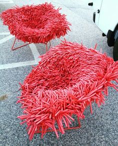 two red chairs sitting next to each other on top of a parking lot in front of a white truck