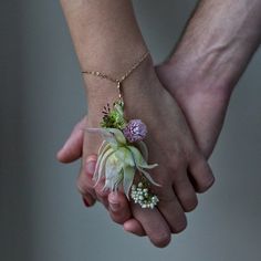 two people holding hands with flowers on them