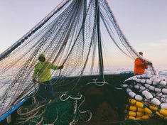 two men are standing on the back of a boat full of lobsters and buoys