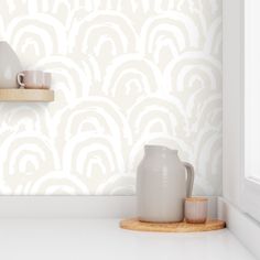 a white vase sitting on top of a counter next to a cup