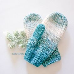 a pair of knitted mittens sitting on top of a white table next to a green plant