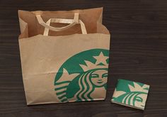 a brown paper bag sitting on top of a wooden table next to a small piece of food