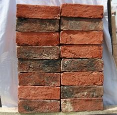 a pile of red bricks sitting on top of a cement slab