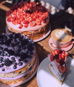 there are three cakes on the table and one is topped with strawberries, blueberries, and blackberries