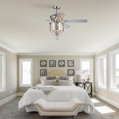 a bedroom with a bed, ceiling fan and pictures hanging on the wall above it