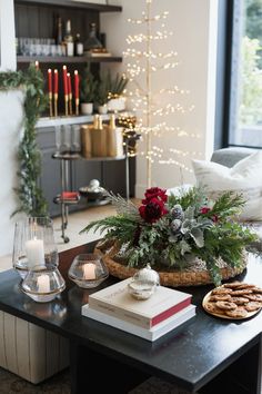 a living room decorated for christmas with candles, books and flowers on the coffee table