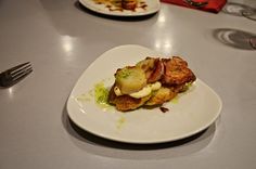 a white plate topped with food on top of a table next to a fork and knife