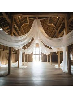 the inside of a building with white drapes hanging from it's ceiling and wooden floors