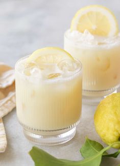 two glasses filled with lemonade sitting next to each other on top of a table