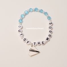 a beaded bracelet with the words out of the woods and an origami arrow