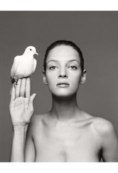 a black and white photo of a woman holding a bird in her hand with one hand