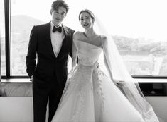 a bride and groom pose in front of a window