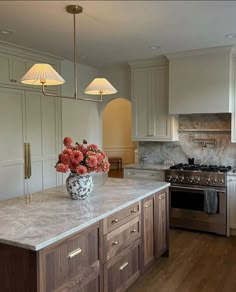 a kitchen with an island, stove and sink in the center is decorated with red flowers