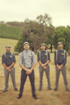 a group of men standing next to each other in front of a field with trees