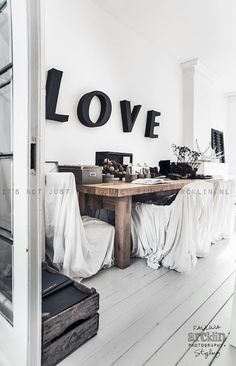 a dining room table covered in white cloths with love letters on the wall above it