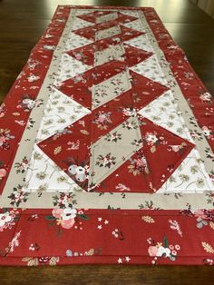 a red and white quilted table runner with flowers on it