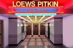 the entrance to loews pittkin theater is lit up with red and blue lights