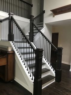 a white staircase with black railing and wooden handrails in an empty room next to a desk