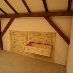 an empty room with wooden beams and drawers in the center, along with carpeted flooring