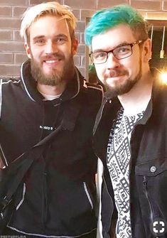 two men standing next to each other in front of a brick wall