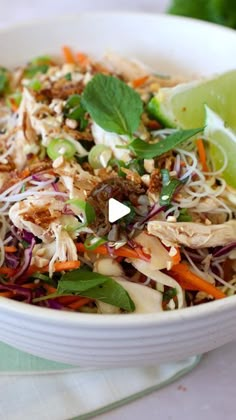 a white bowl filled with food and garnished with limes on the side