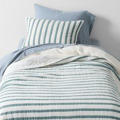 a bed with blue and white striped comforter next to a pillow on top of it