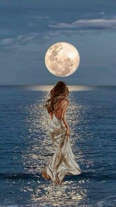 a woman standing in the water with her back to the camera, looking at the moon