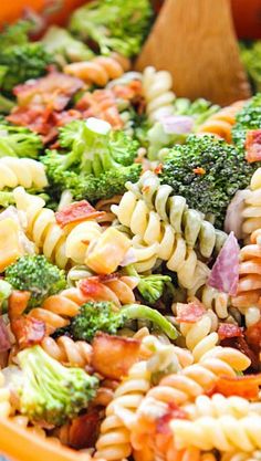 pasta salad with bacon and broccoli in a bowl next to a wooden spoon