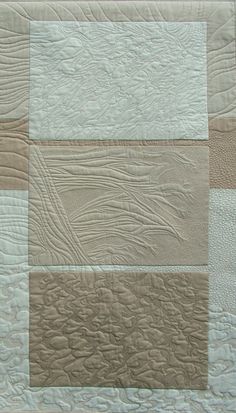 a close up of a quilt on a bed with white and brown squares in the center