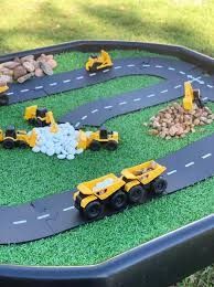 a toy truck track with construction vehicles on it and rocks in the middle to play