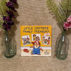 the little critter's family treasury book is next to two vases with flowers in them