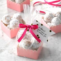 two pink boxes filled with white chocolate covered donuts and a ribbon tied around the top