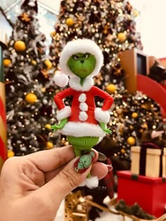 a hand holding a toy in front of a christmas tree