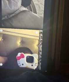 a hello kitty cell phone sitting on top of a table next to a person's feet