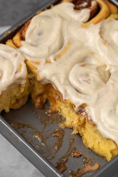 a pan filled with cinnamon rolls covered in icing