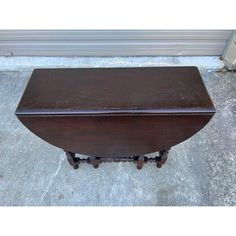 an old wooden table with wheels on the bottom and one drawer at the top, sitting in front of a garage door