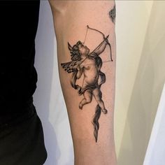 a woman with a tattoo on her arm holding a bow and arrow in the shape of a cupid