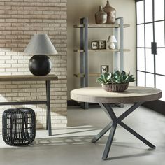 a living room filled with furniture and a lamp on top of a wooden table in front of a brick wall