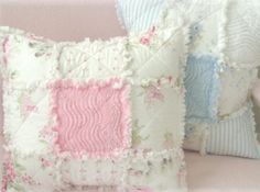 two decorative pillows are sitting on a white couch with pink and blue trimmings