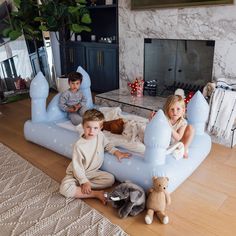 three children sitting on an inflatable bed with stuffed animals