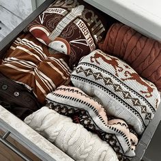 an open drawer filled with sweaters and pillows